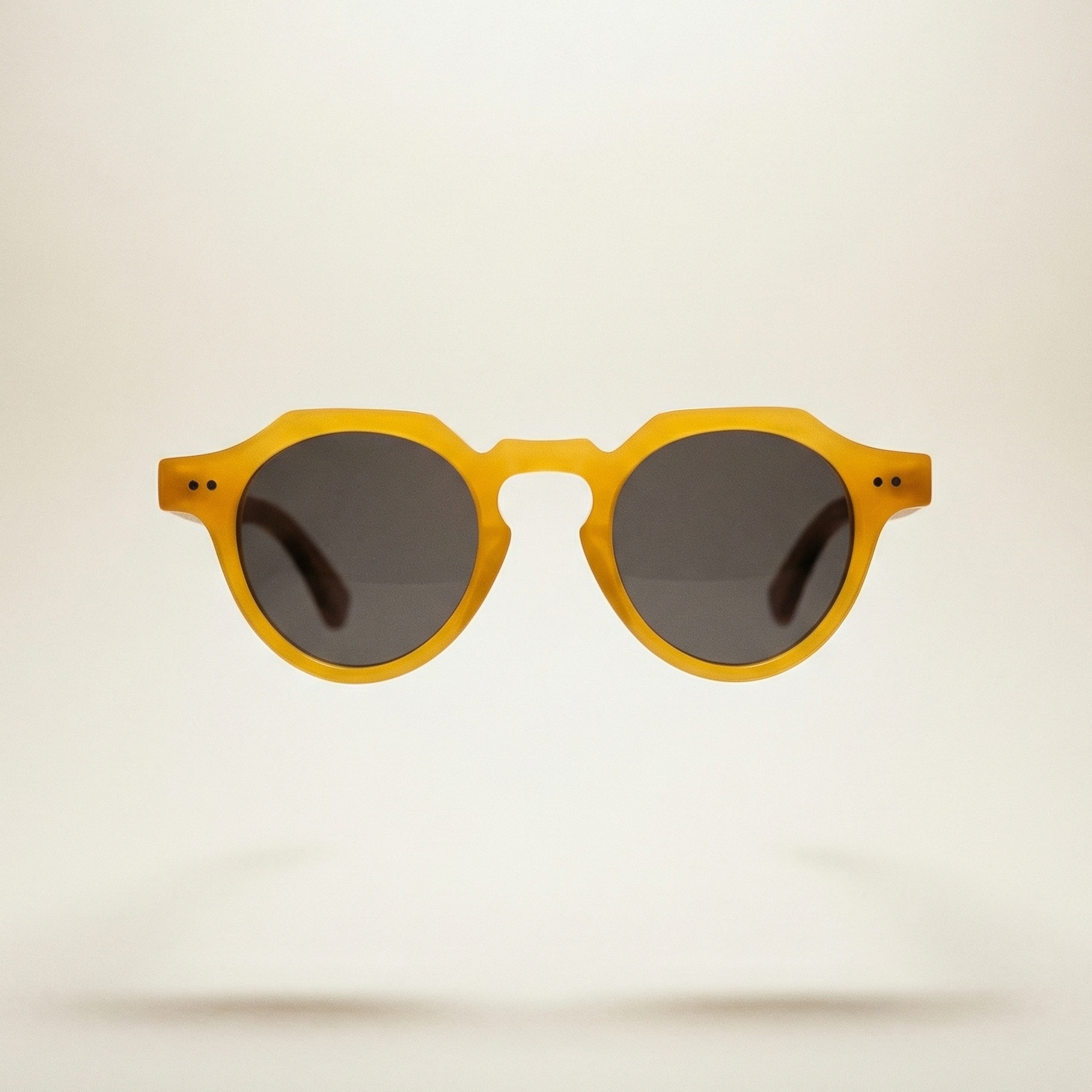 Yellow sunglasses with dark lenses on a light beige background